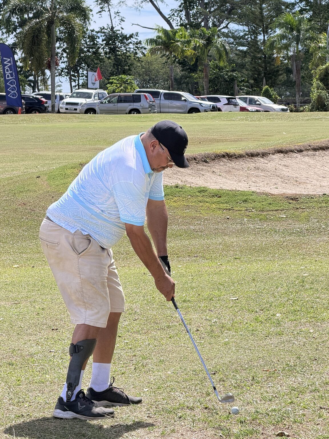 A golfer playing an approach shot beside a bunker