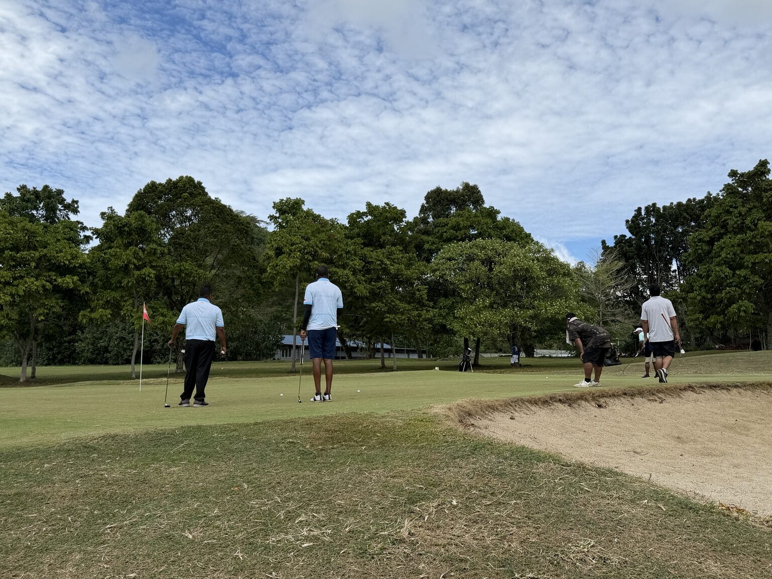 Golfers and officials gathered around a putting green