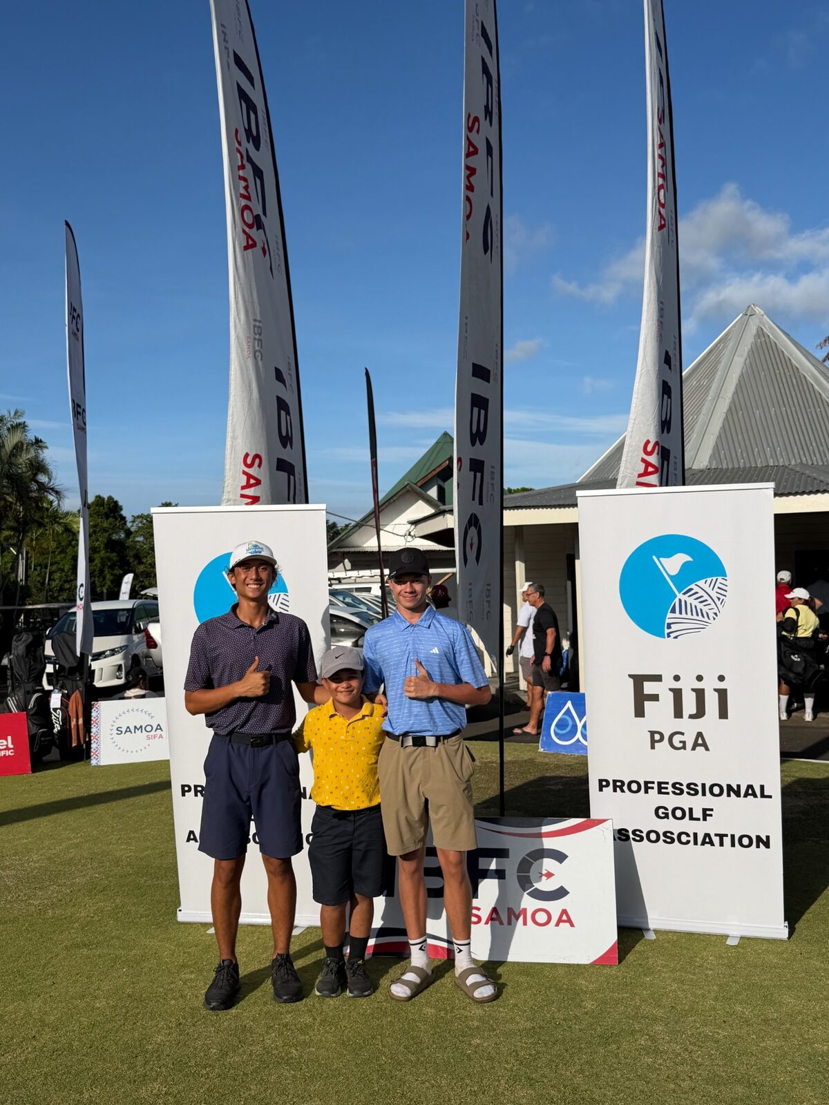 Junior golfers and Pacific golf representatives standing beside event signage
