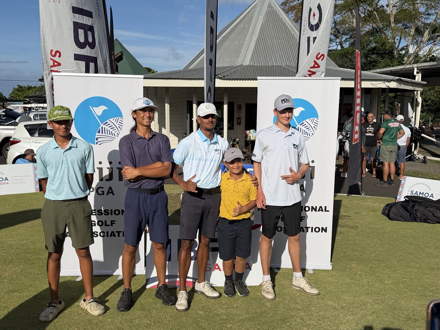 A group of Samoa Open players standing beside tournament signage